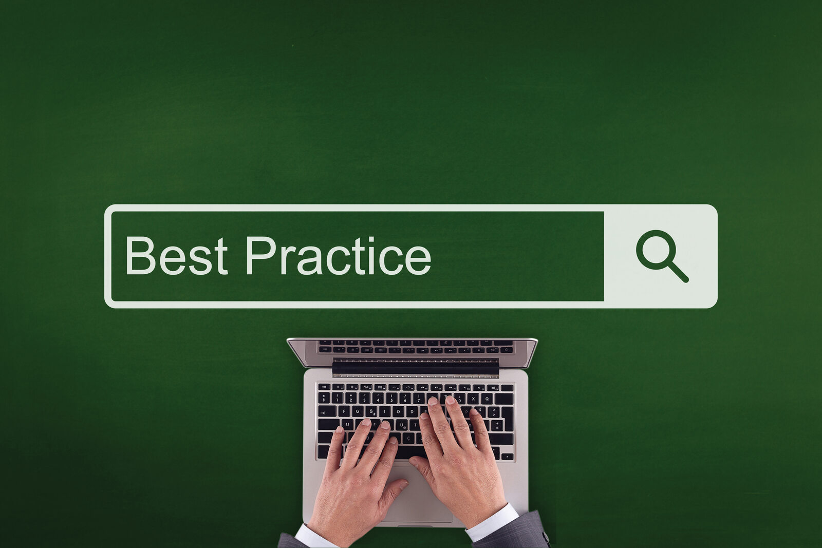 Overhead shot of a businessman’s hands typing on a laptop with a search bar spelling out “best practice”