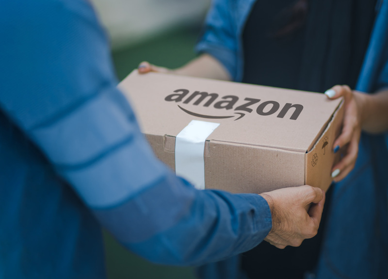 An Amazon employee handing an Amazon package to a seller, representing the concept of dropshipping