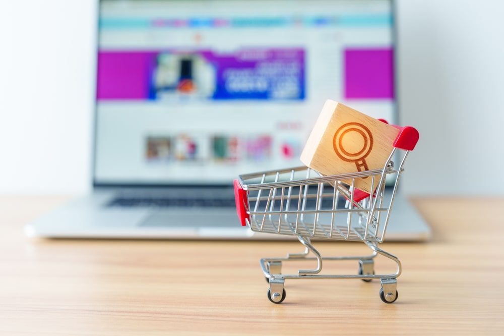 Shopping cart with magnifying icon block and laptop computer