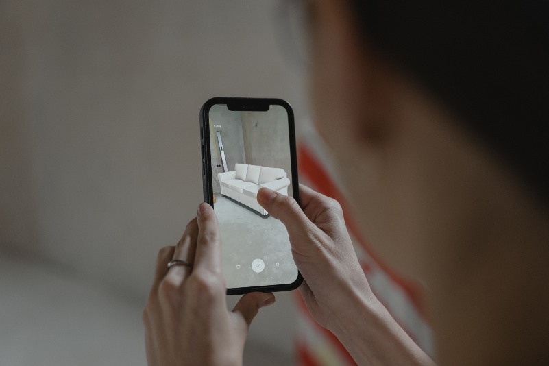 shot of a person using augmented reality technology in their house while shopping for a sofa