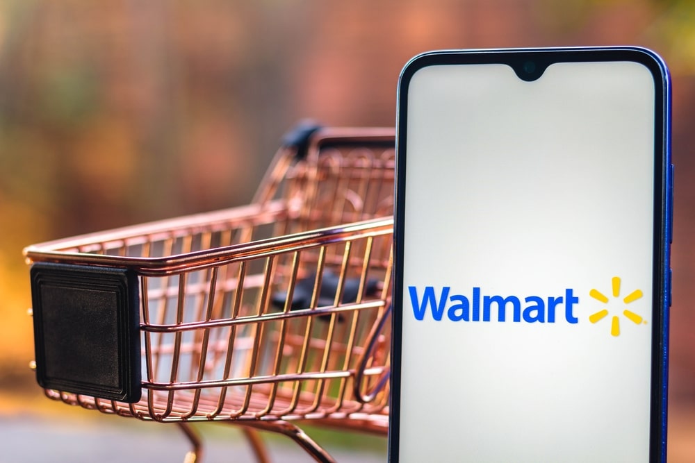 a small grocery cart beside a smartphone with the walmart online logo on its screen