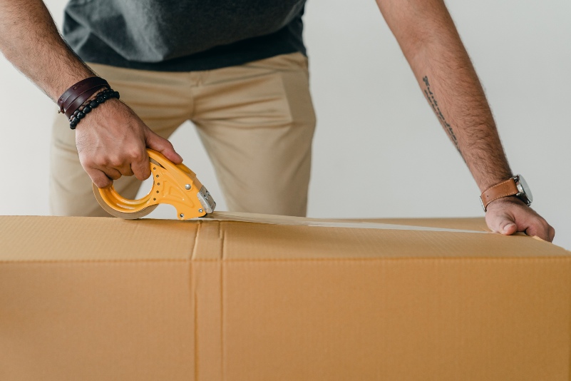 closeup shot of a person sealing a package box with packaging tape